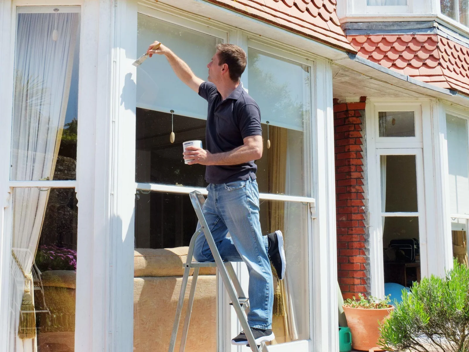 Schilder schildert een raamkozijn aan de buitenkant van een woning